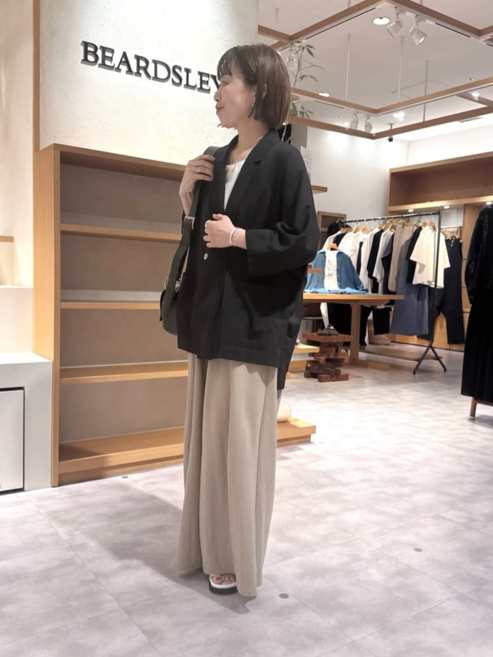 ブラック系のテーラードジャケット、ベージュ系のその他パンツ、ホワイト系のサンダルを着用したレディースの春コーディネートの4枚目の写真