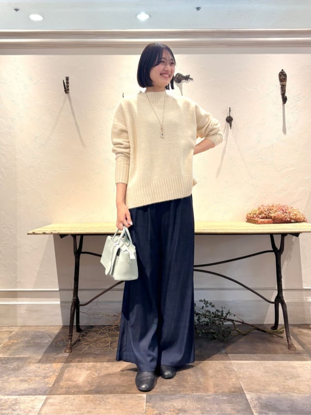 ブルー系のその他パンツ、グリーン系のハンドバッグ、ホワイト系のニット/セーターを着用したレディースの冬コーディネートの4枚目の写真