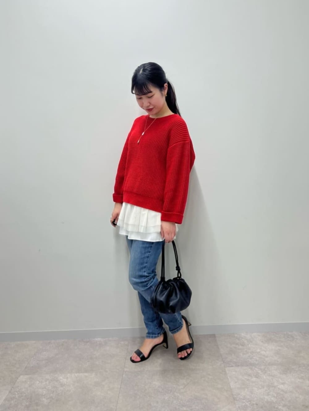 ブルー系のデニムパンツ、ホワイト系のタンクトップ、レッド系のニット/セーターを着用したレディースの冬コーディネートの3枚目の写真