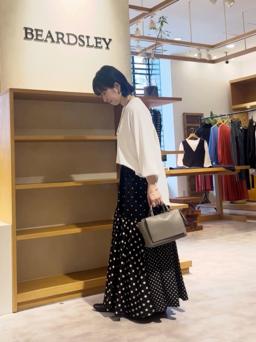 ブラック系のスカート、グレー系のハンドバッグ、ホワイト系のシャツ/ブラウスを着用したレディースの春コーディネートの3枚目の写真