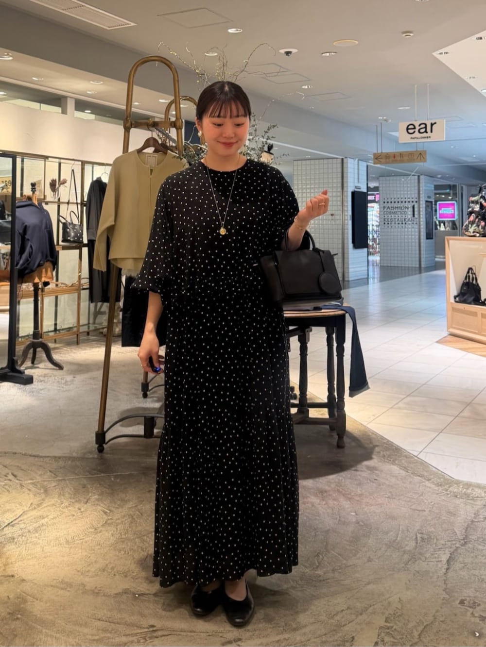 ブラック系のハンドバッグ、ブラック系のワンピースを着用したレディースの春コーディネートの2枚目の写真