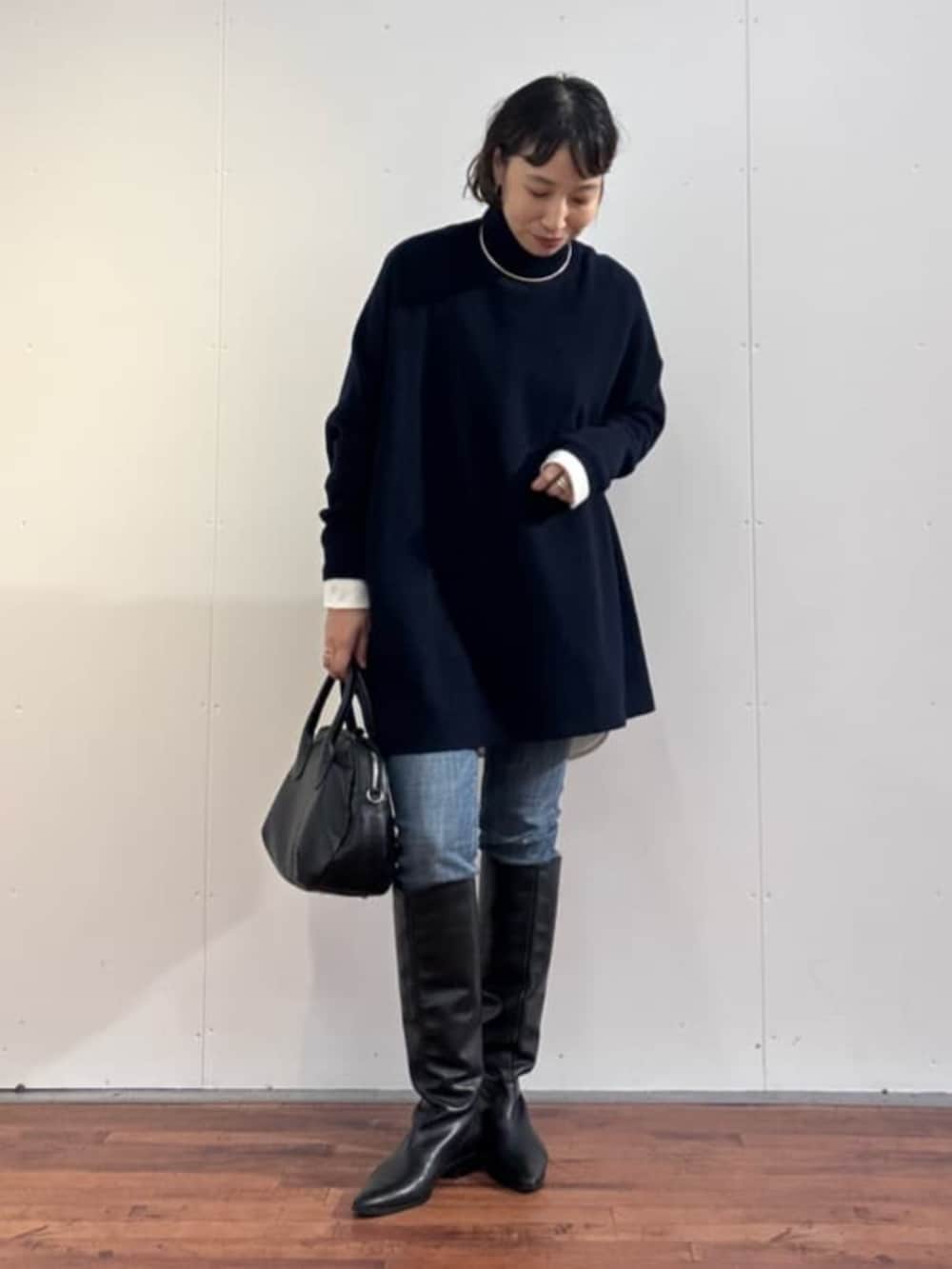 ブルー系のデニムパンツ、ブラック系のトートバッグ、ブルー系のニット/セーターを着用したレディースの秋コーディネートの3枚目の写真