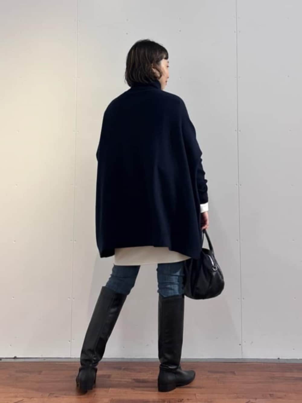 ブルー系のデニムパンツ、ブラック系のトートバッグ、ブルー系のニット/セーターを着用したレディースの秋コーディネートの5枚目の写真