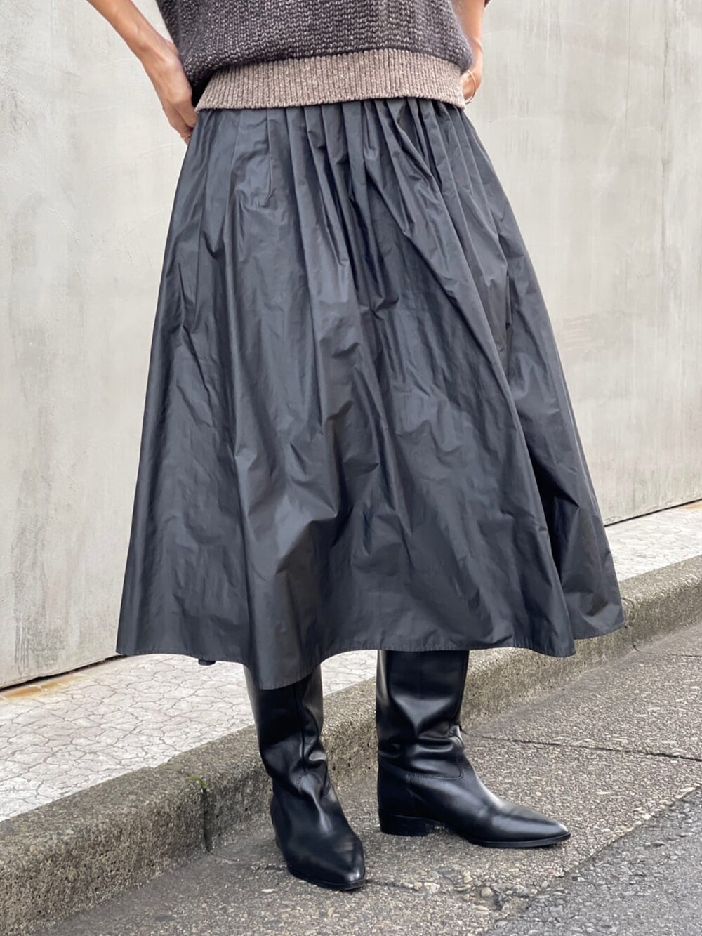 グレー系のスカート、ブルー系のチェスターコート、ブラウン系のニット/セーターを着用したレディースの秋コーディネートの4枚目の写真