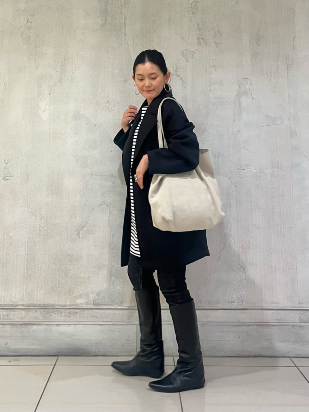 ブルー系のTシャツ/カットソー、ブラック系のデニムパンツ、ブラック系のピーコートを着用したレディースの冬コーディネートの4枚目の写真