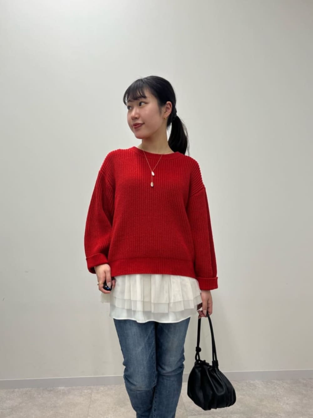 ブルー系のデニムパンツ、ホワイト系のタンクトップ、レッド系のニット/セーターを着用したレディースの冬コーディネートの7枚目の写真