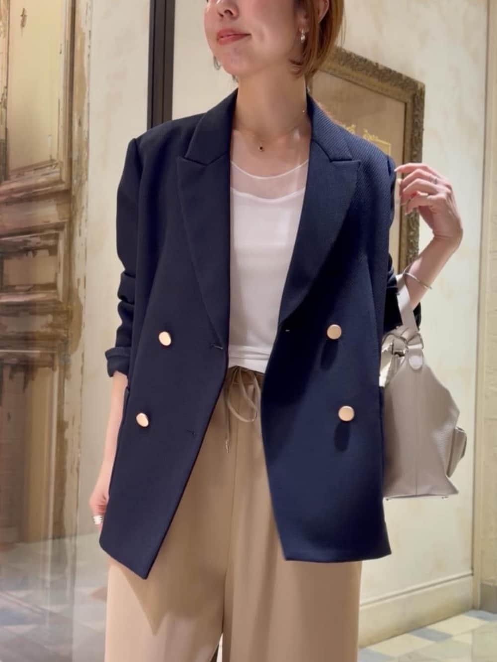 ブルー系のテーラードジャケット、ホワイト系のキャミソール、イエロー系のその他パンツを着用したレディースの春コーディネートの3枚目の写真