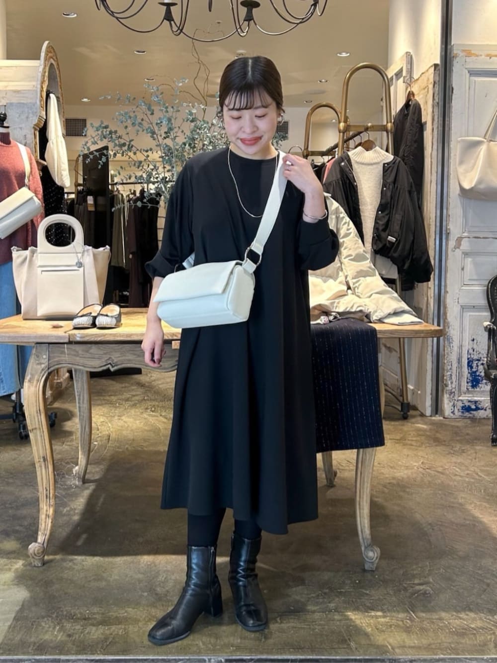 ホワイト系のショルダーバッグ、ブラック系のワンピースを着用したレディースの冬コーディネートの3枚目の写真