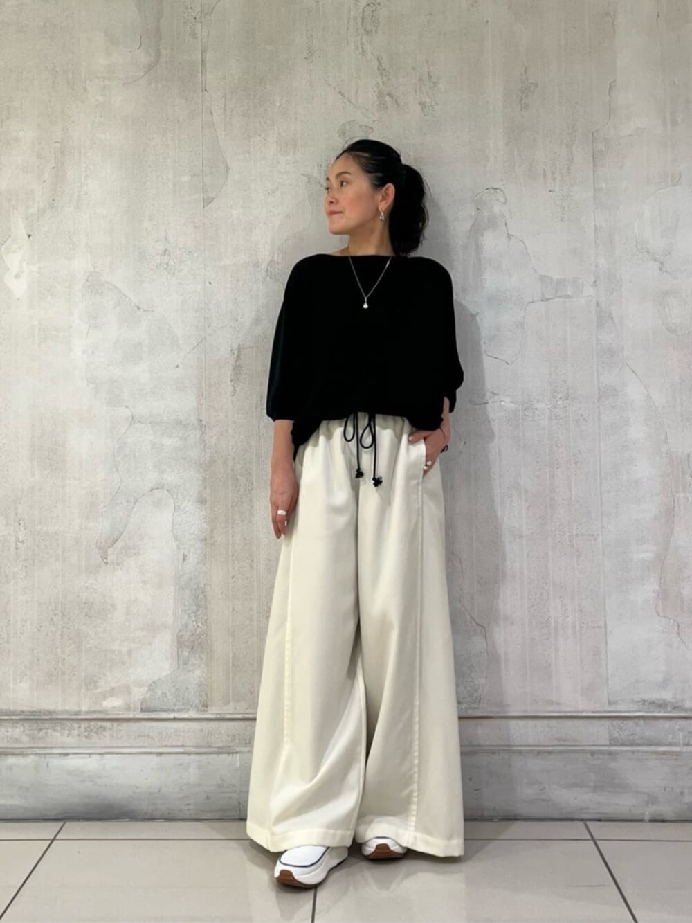 ブラック系のニット/セーター、ホワイト系のその他パンツを着用したレディースの冬コーディネートの7枚目の写真