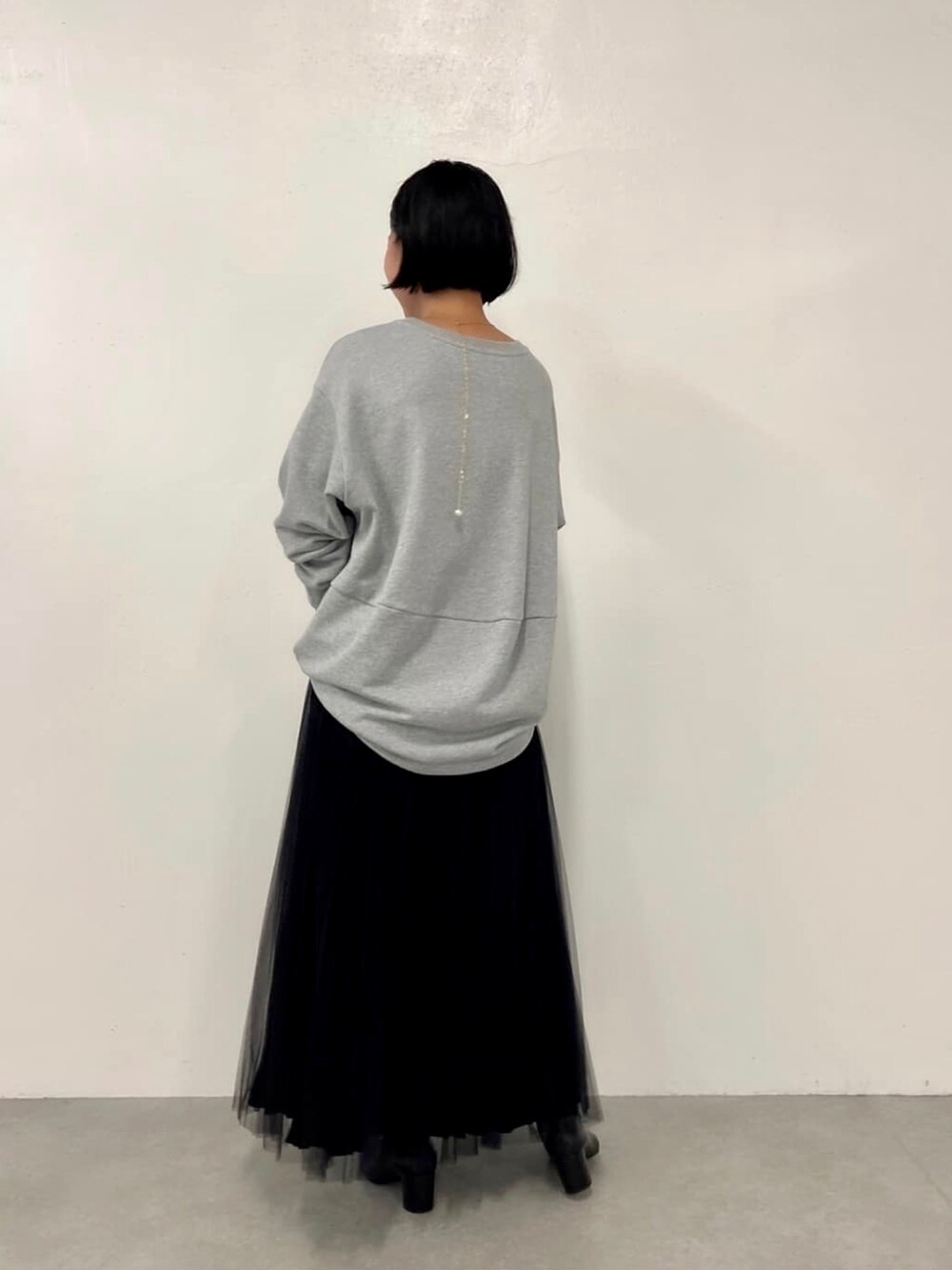 グレー系のスウェット、ブラック系のスカート、ゴールド系のネックレスを着用したレディースの夏コーディネートの2枚目の写真