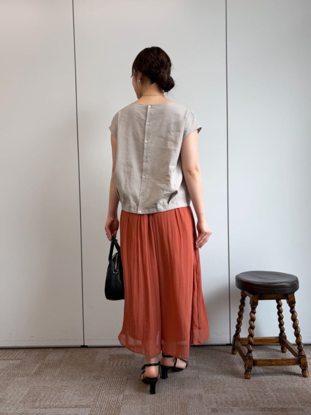 ブラック系のボストンバッグ、オレンジ系のその他パンツ、ベージュ系のシャツ/ブラウスを着用したレディースの冬コーディネートの3枚目の写真