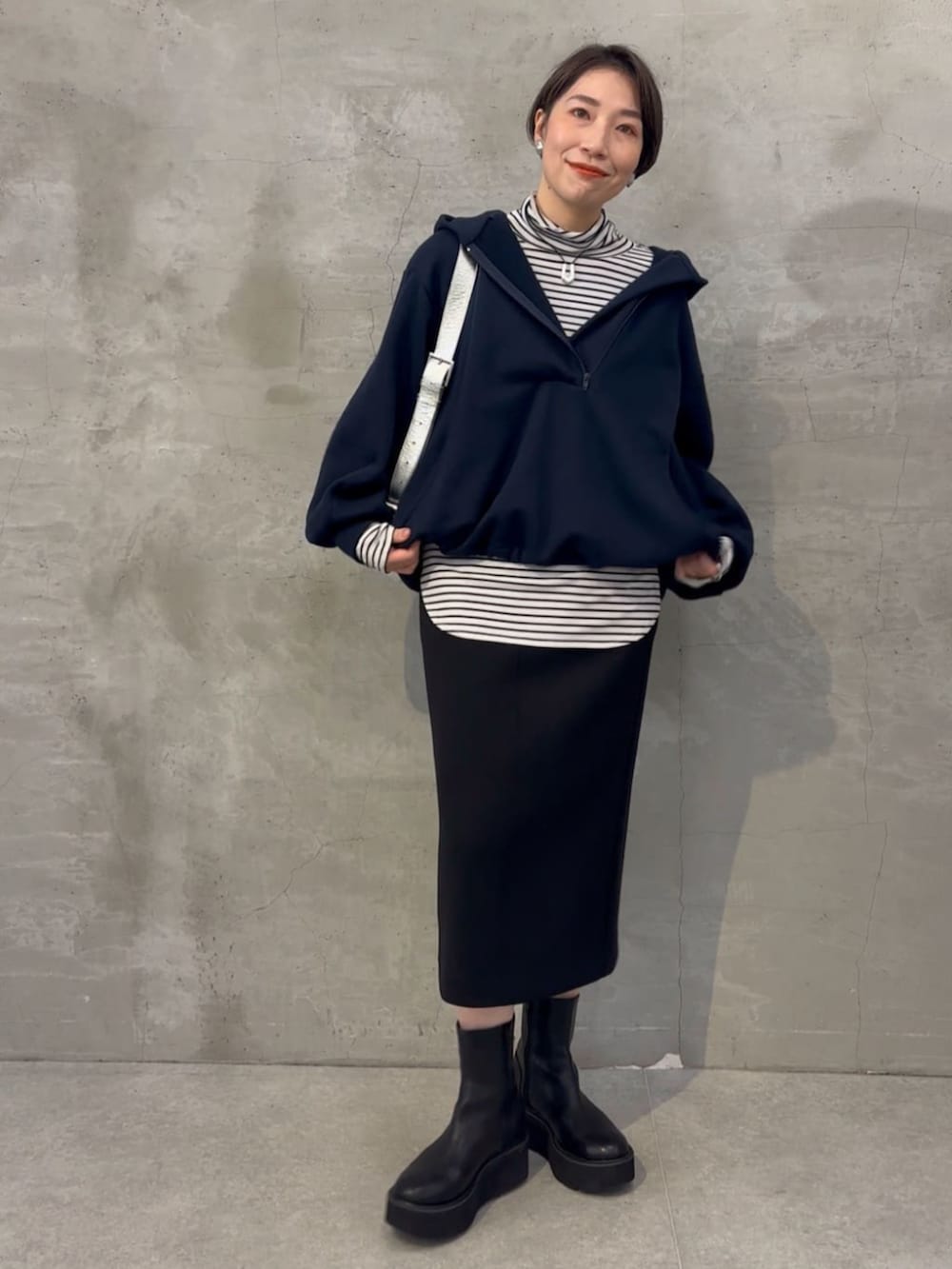 ブラック系のブーツ、ブラック系のスカート、ブルー系のパーカーを着用したレディースの冬コーディネートの2枚目の写真