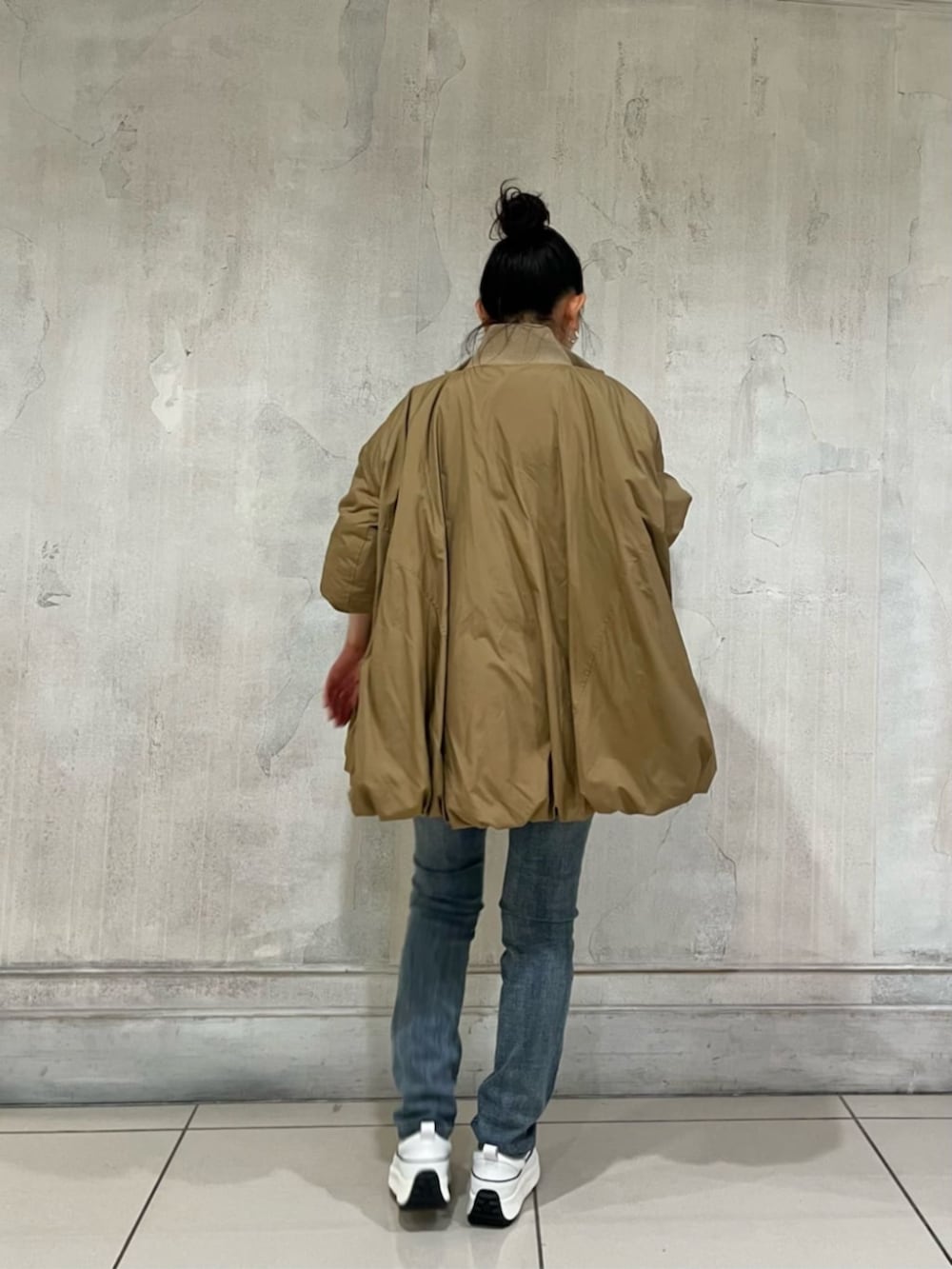 ホワイト系のスニーカー、ブルー系のデニムパンツ、イエロー系のその他アウターを着用したレディースの冬コーディネートの4枚目の写真