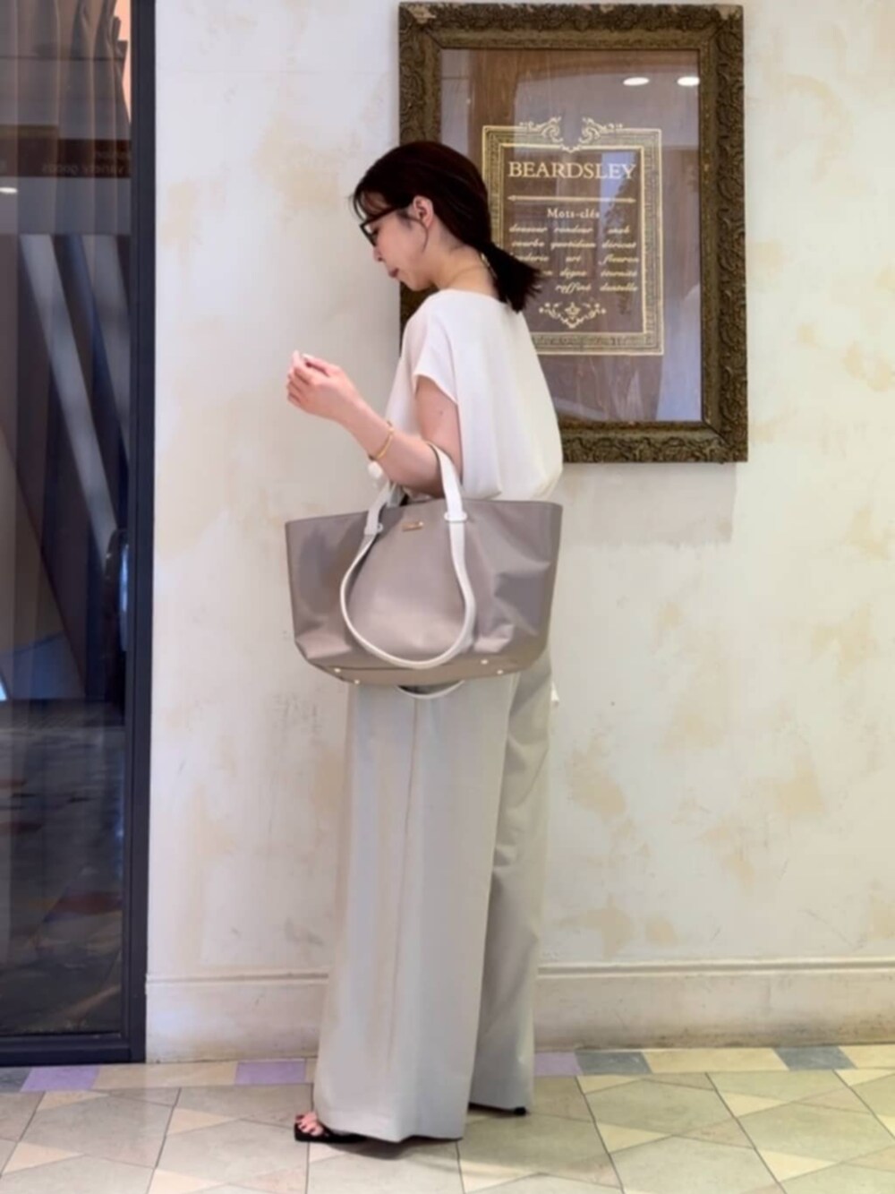 ベージュ系のその他パンツ、ホワイト系のシャツ/ブラウス、グレー系のトートバッグを着用したレディースの春コーディネートの3枚目の写真