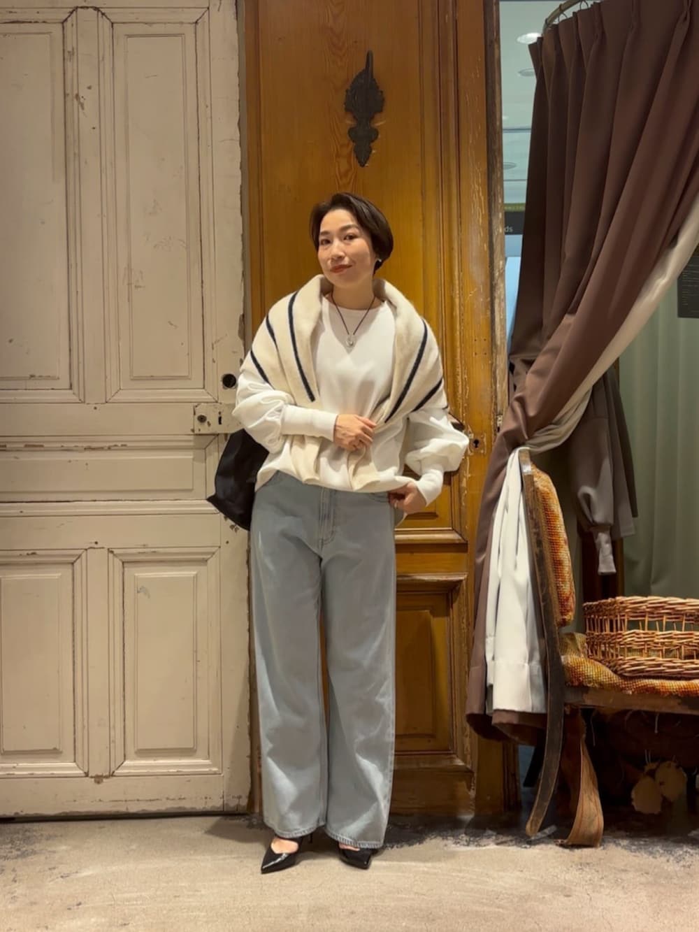 ブルー系のデニムパンツ、ホワイト系のTシャツ/カットソー、ブラック系のショルダーバッグを着用したレディースの冬コーディネートの2枚目の写真