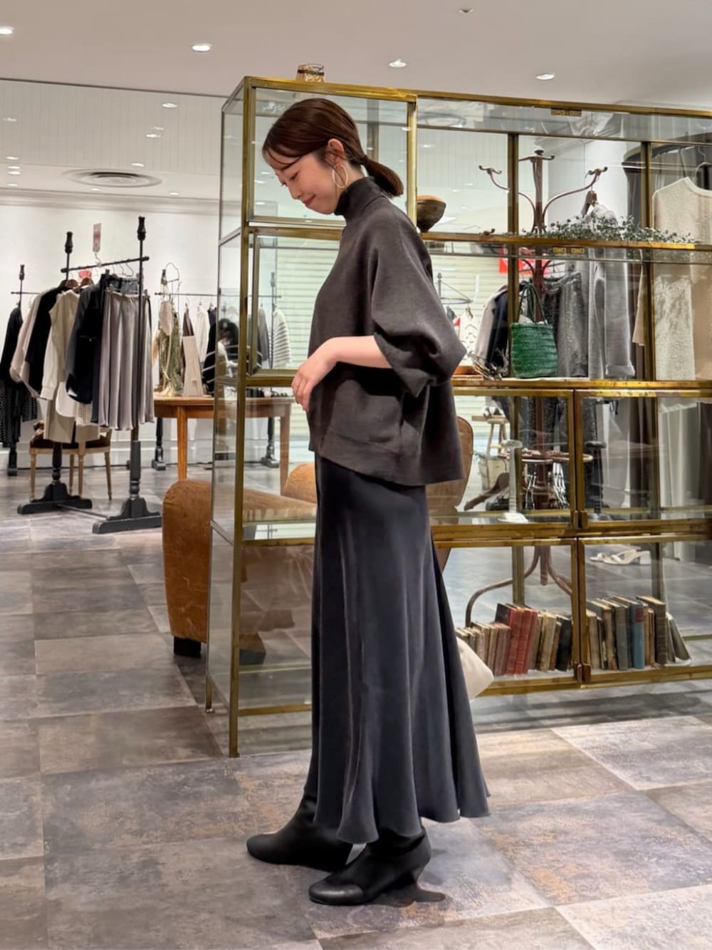 ブラック系のスカート、グレー系のニット/セーター、ベージュ系のハンドバッグを着用したレディースの冬コーディネートの3枚目の写真