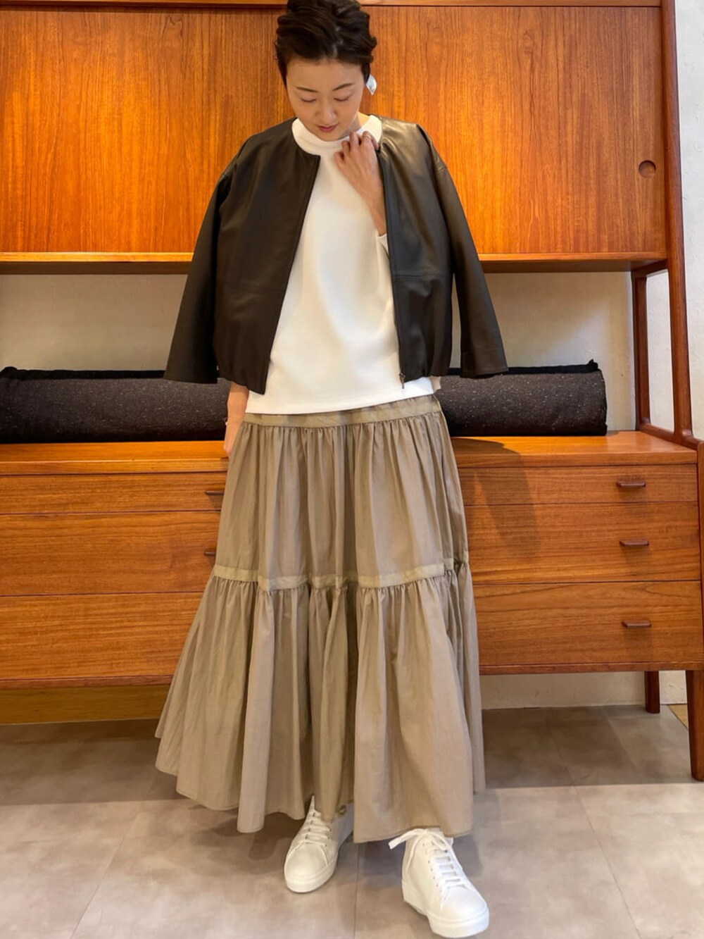 ホワイト系のTシャツ/カットソー、ベージュ系のスカート、ホワイト系のスニーカーを着用したレディースの冬コーディネートの2枚目の写真