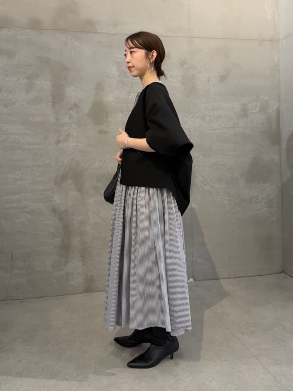 ブラック系のボストンバッグ、ブラック系のカーディガン/ボレロ、ブルー系のワンピースを着用したレディースの冬コーディネートの2枚目の写真