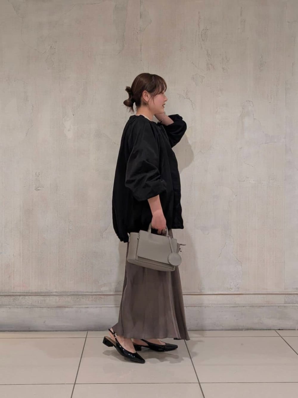 グリーン系のスカート、グレー系のハンドバッグ、ブラック系のノーカラージャケットを着用したレディースの春コーディネートの2枚目の写真
