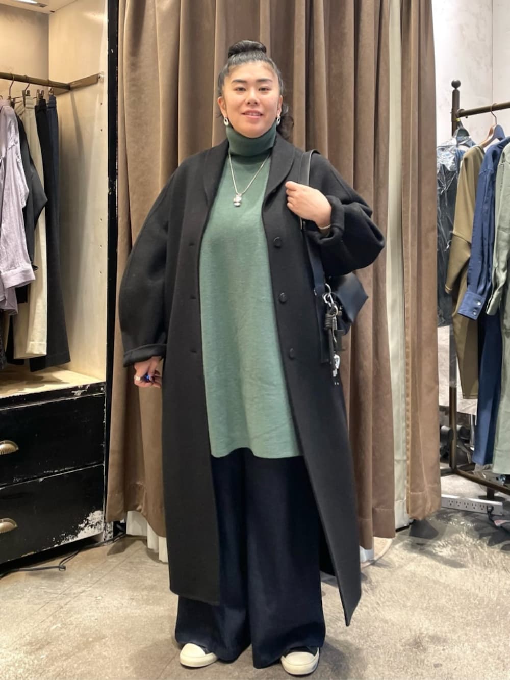 ブラック系のショルダーバッグ、ブラック系のその他アウター、グリーン系のニット/セーターを着用したレディースの冬コーディネートの3枚目の写真