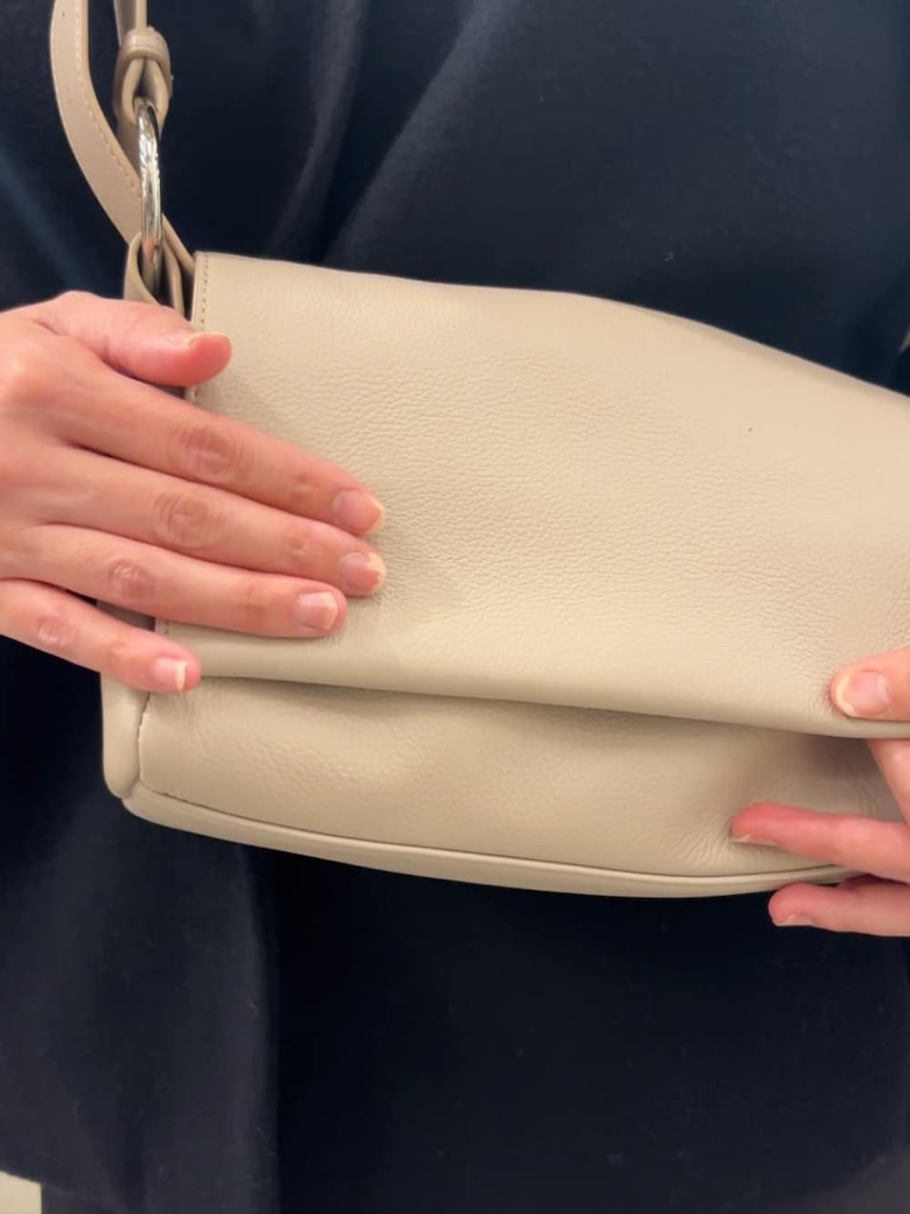 ブラック系のノーカラーコート、ブラック系のその他パンツ、ホワイト系のショルダーバッグを着用したレディースの冬コーディネートの9枚目の写真