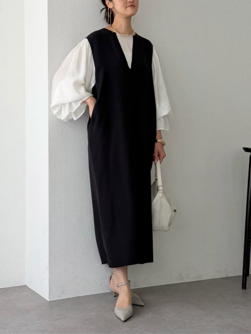 ホワイト系のシャツ/ブラウス、ブラック系のジャンパースカート、グレー系のパンプスを着用したレディースの秋コーディネートの4枚目の写真