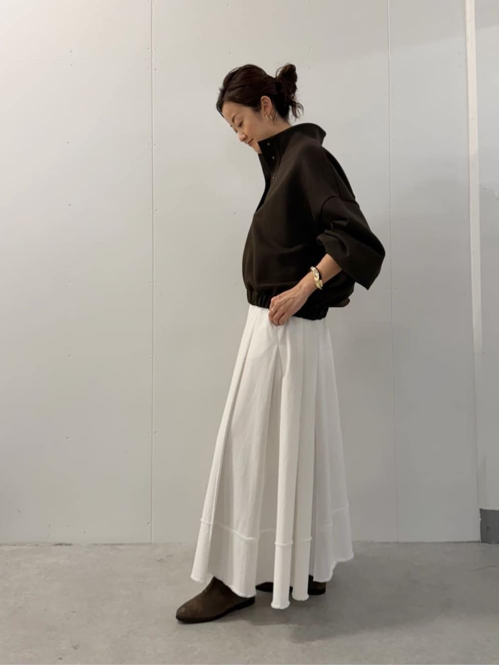 グレー系のハンドバッグ、ホワイト系のスカート、ブラウン系のTシャツ/カットソーを着用したレディースの夏コーディネートの2枚目の写真