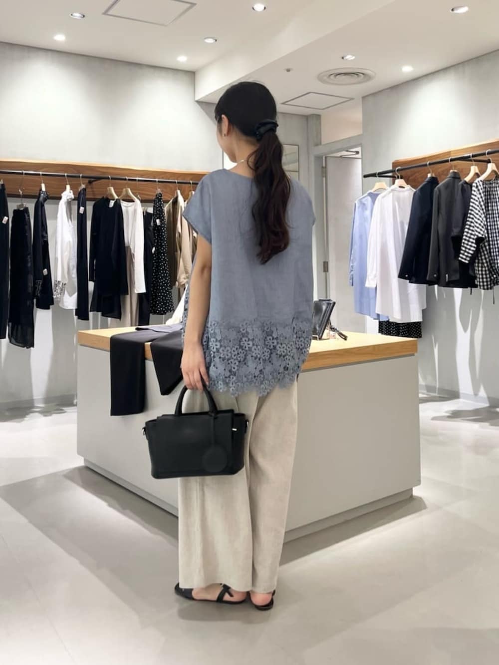 ブラック系のハンドバッグ、ベージュ系のその他パンツ、ブルー系のシャツ/ブラウスを着用したレディースの夏コーディネートの8枚目の写真