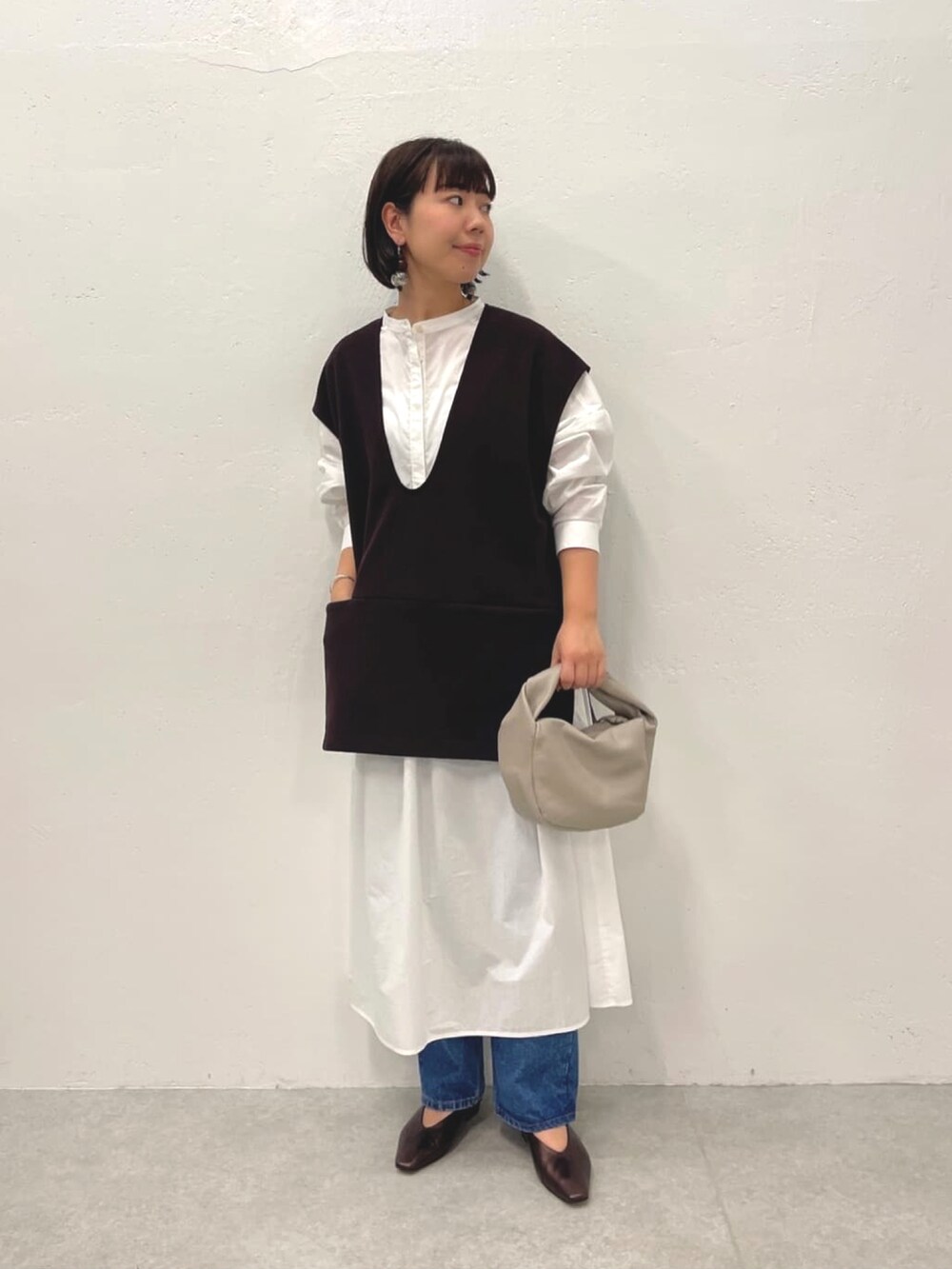 ブラウン系のTシャツ/カットソー、ホワイト系のワンピース、ブルー系のデニムパンツを着用したレディースの秋コーディネートの2枚目の写真