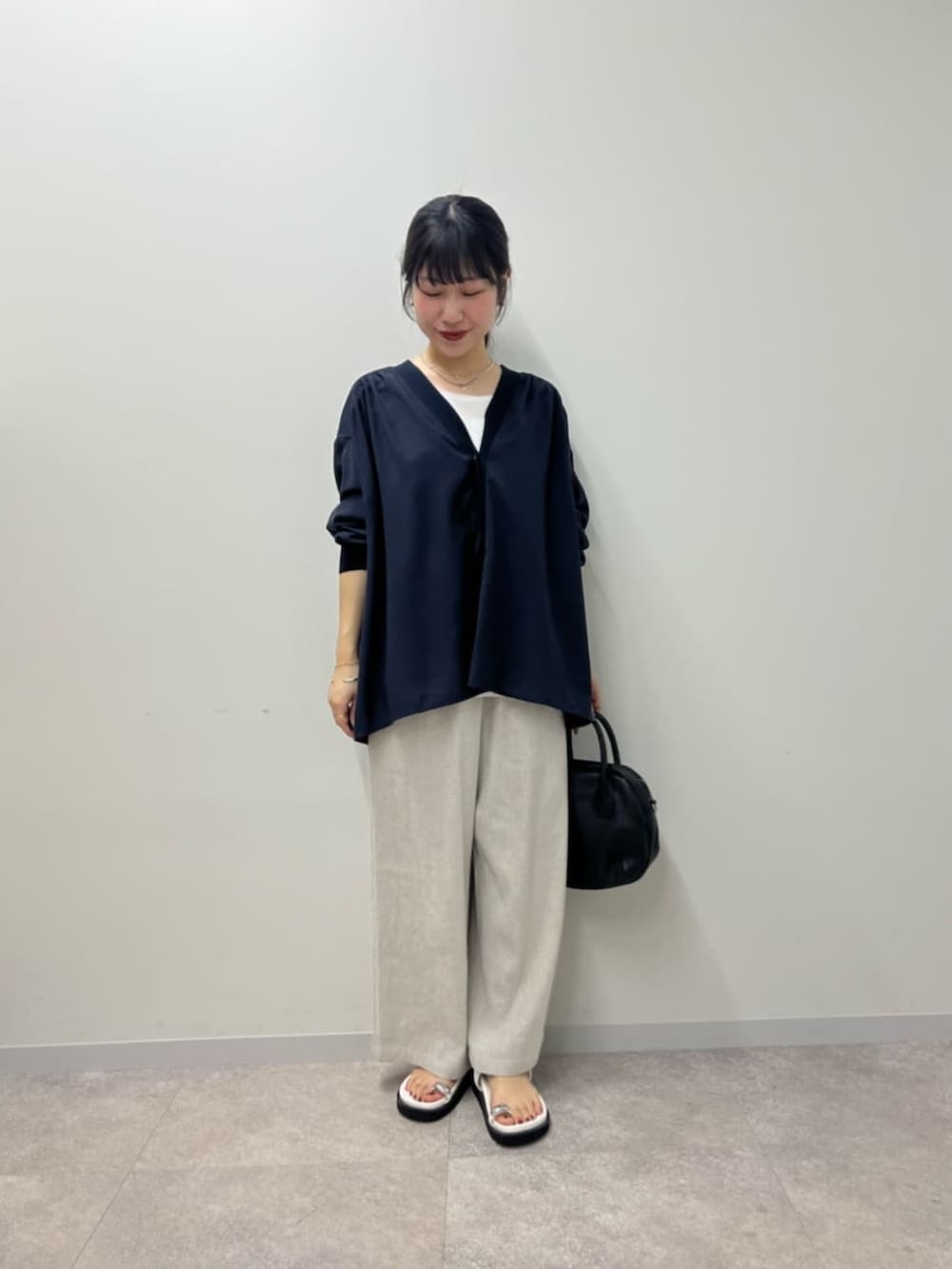 ブラック系のボストンバッグ、ホワイト系のサンダル、ブルー系のシャツ/ブラウスを着用したレディースの春コーディネートの2枚目の写真