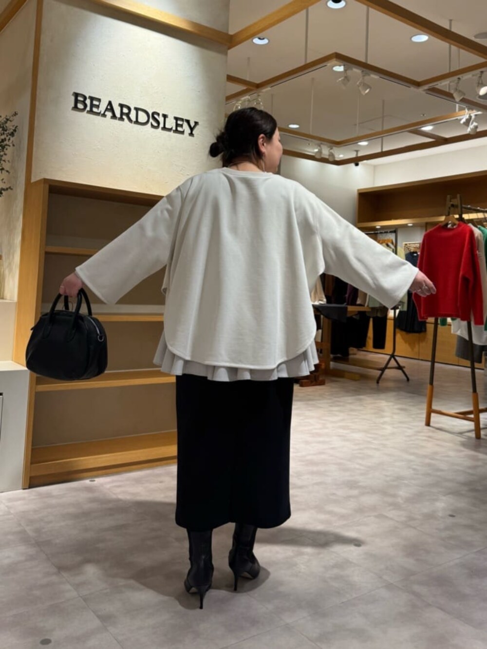 ブラック系のブーツ、ブラック系のスカート、ホワイト系のTシャツ/カットソーを着用したレディースの冬コーディネートの5枚目の写真