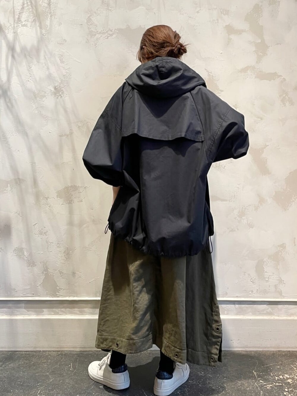 ブラック系のマウンテンパーカー、グリーン系のワンピース、ホワイト系のスニーカーを着用したレディースの春コーディネートの3枚目の写真