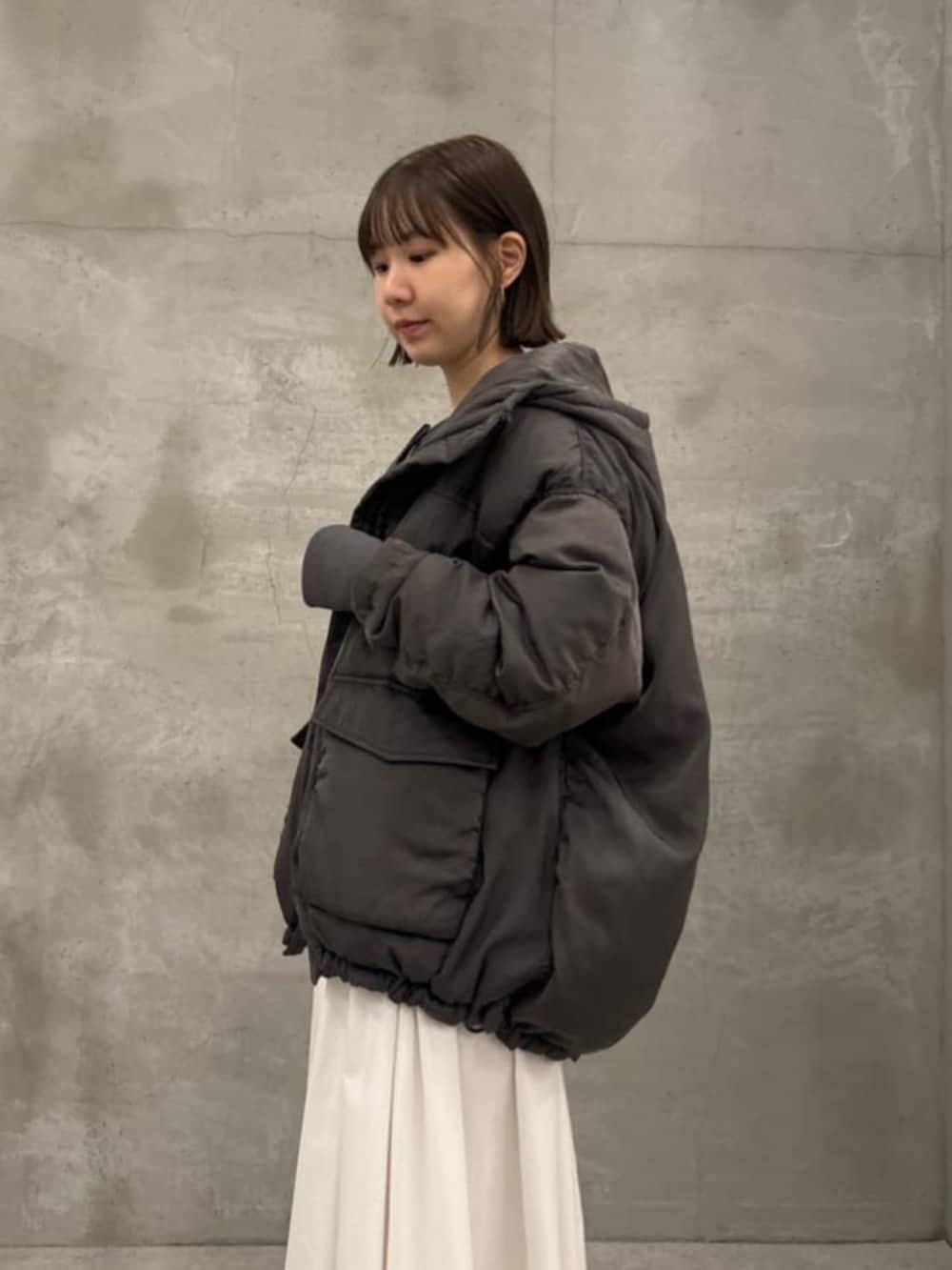 ホワイト系のスカート、グレー系のダウンジャケット/コート、グレー系のTシャツ/カットソーを着用したレディースの秋コーディネートの3枚目の写真
