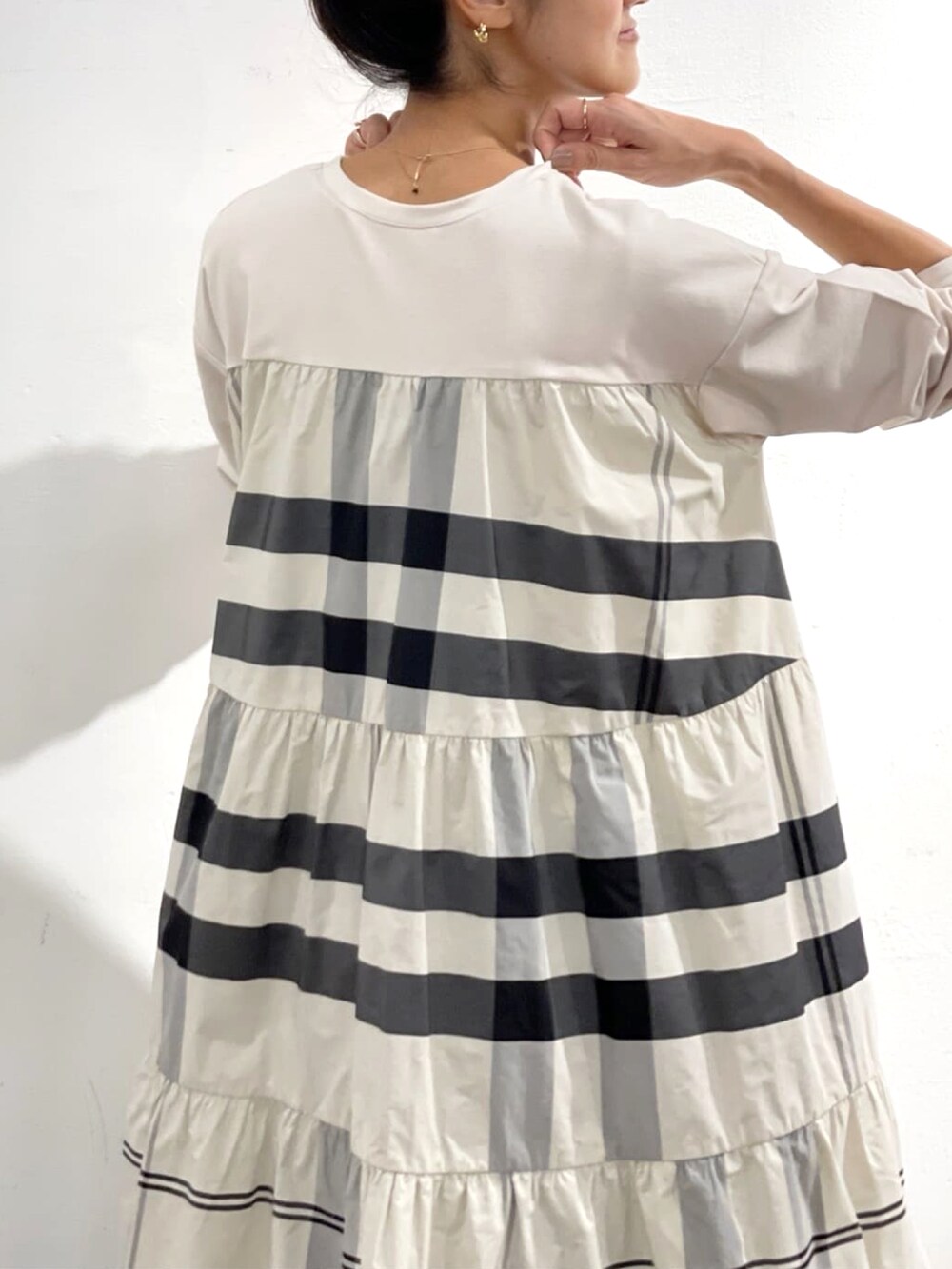 ホワイト系のワンピース、ホワイト系のショルダーバッグ、ブルー系のデニムパンツを着用したレディースの秋コーディネートの2枚目の写真