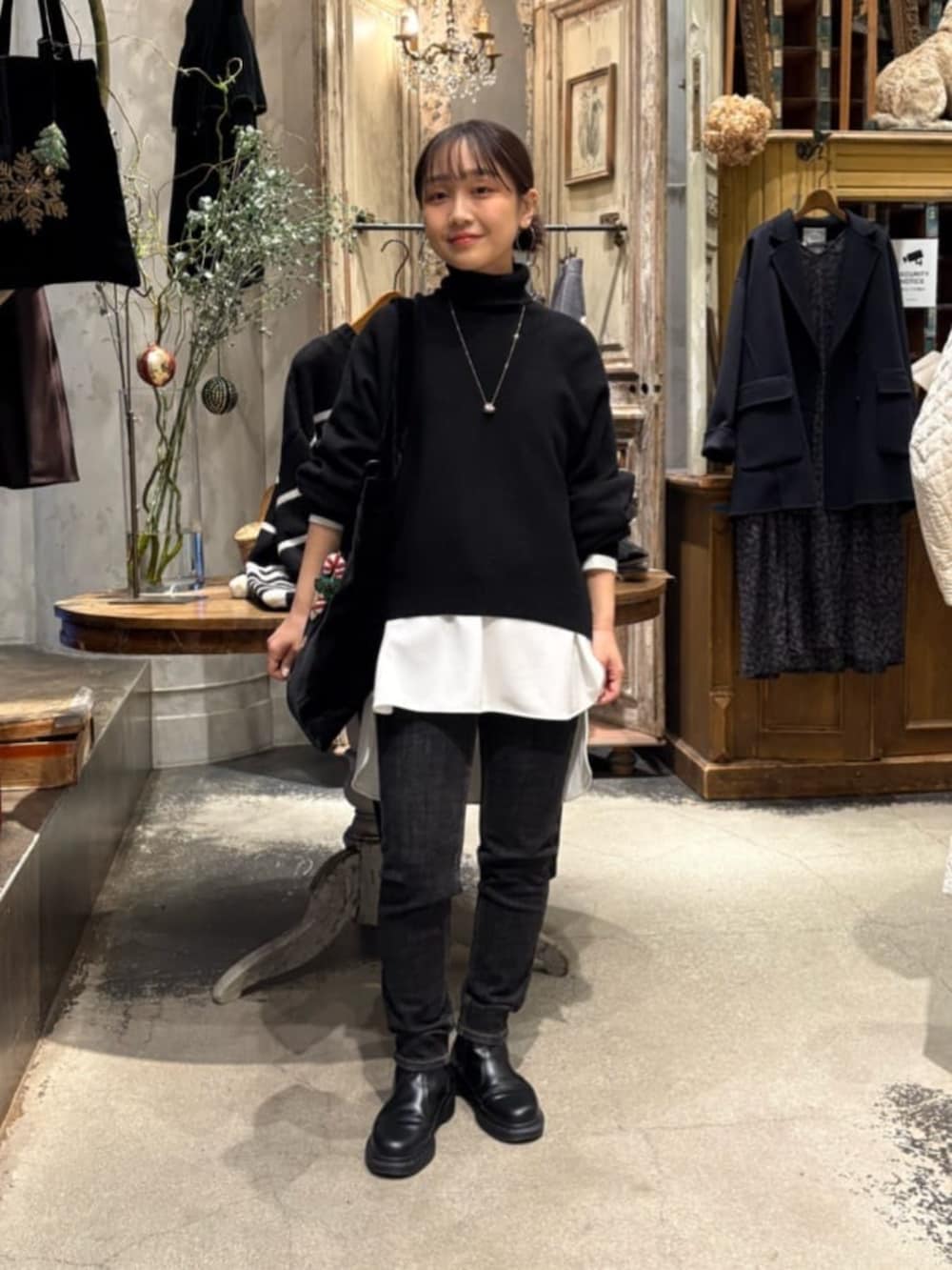 ブラック系のニット/セーター、ブラック系のデニムパンツ、ホワイト系のシャツ/ブラウスを着用したレディースの冬コーディネートの4枚目の写真