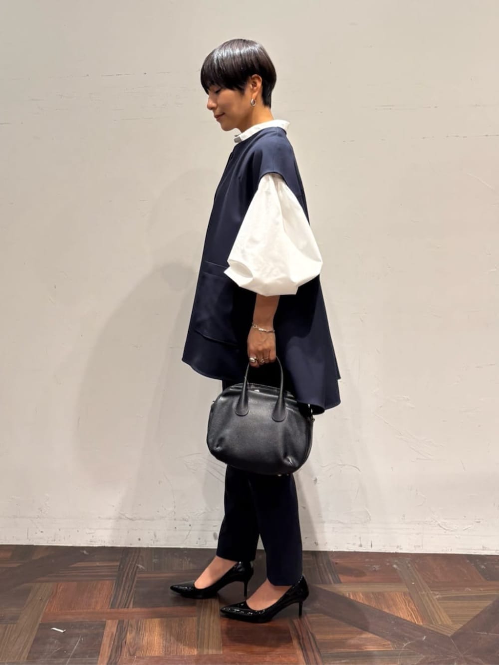 ブラック系のボストンバッグ、ブルー系のベスト、ホワイト系のシャツ/ブラウスを着用したレディースの冬コーディネートの3枚目の写真