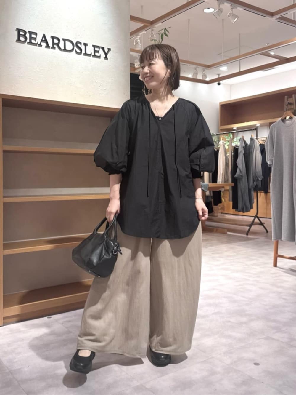 ブラック系のボストンバッグ、ベージュ系のその他パンツ、ブラック系のシャツ/ブラウスを着用したレディースの春コーディネートの3枚目の写真