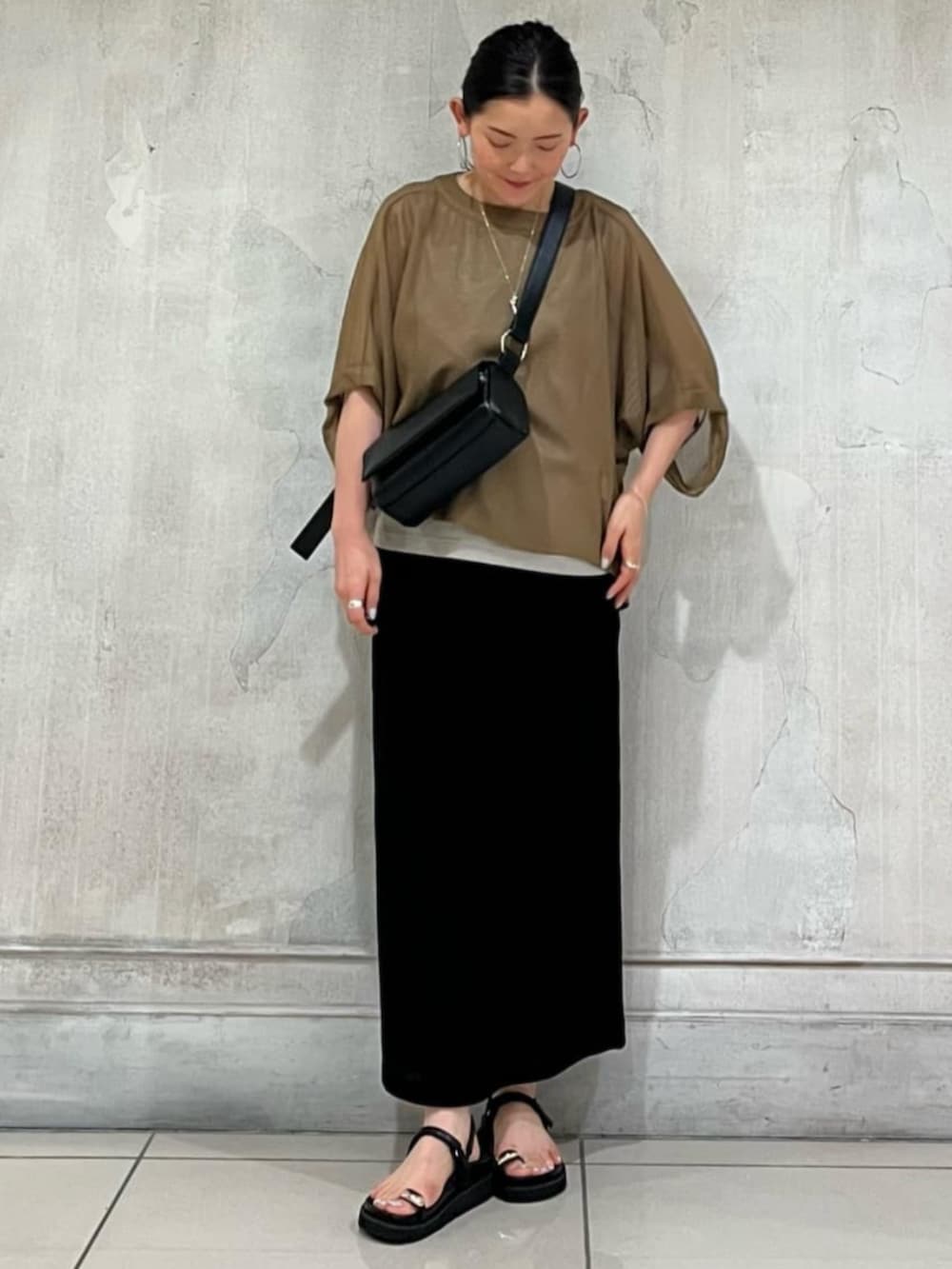 ブラック系のショルダーバッグ、ブラック系のスカート、イエロー系のTシャツ/カットソーを着用したレディースの春コーディネートの3枚目の写真