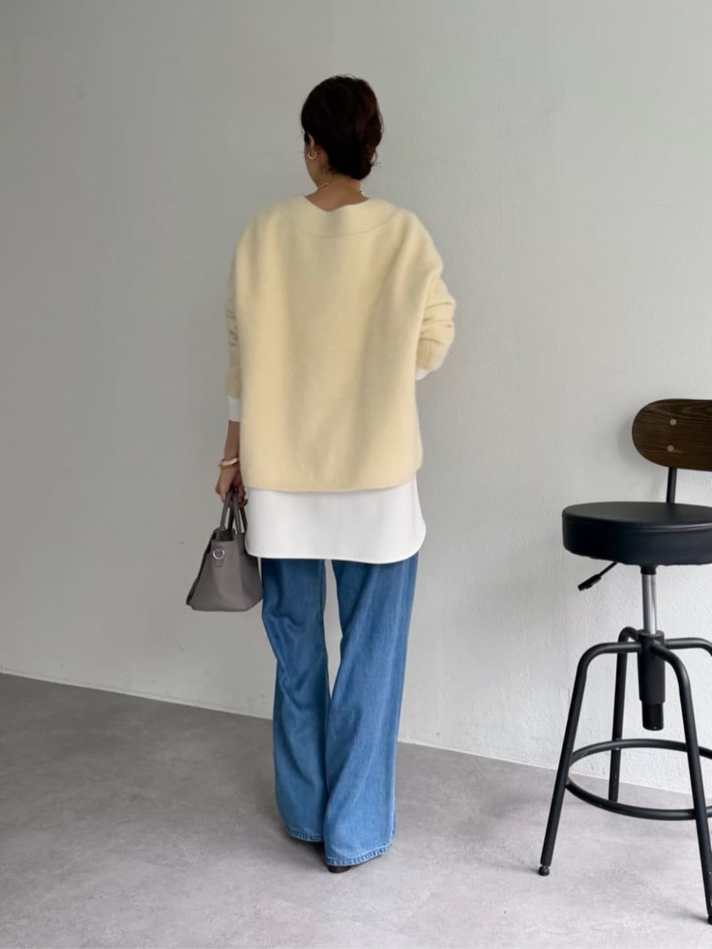 グレー系のハンドバッグ、ホワイト系のシャツ/ブラウス、イエロー系のニット/セーターを着用したレディースの秋コーディネートの6枚目の写真