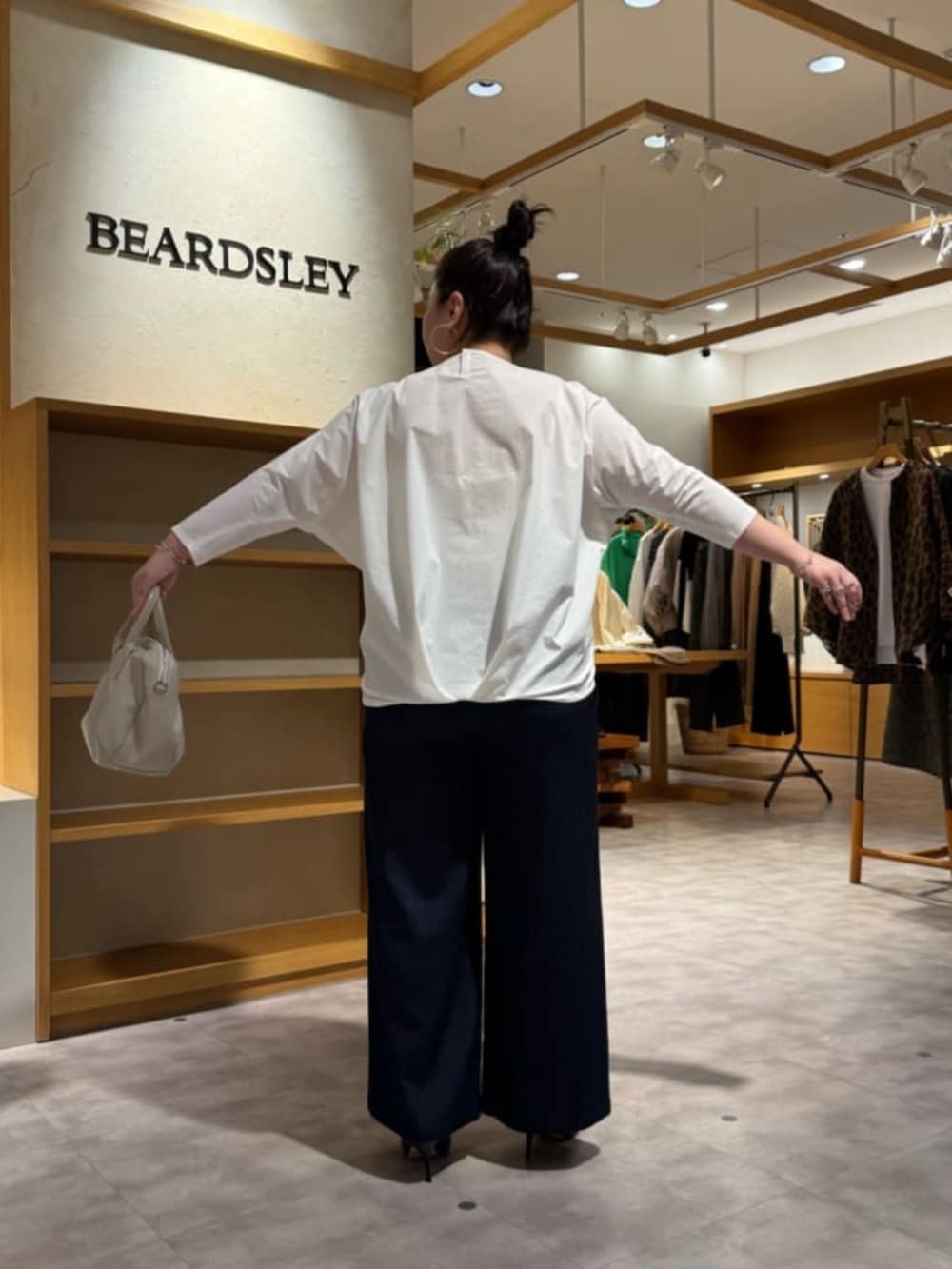 グレー系のボストンバッグ、ブラック系のブーツ、ホワイト系のシャツ/ブラウスを着用したレディースの冬コーディネートの4枚目の写真