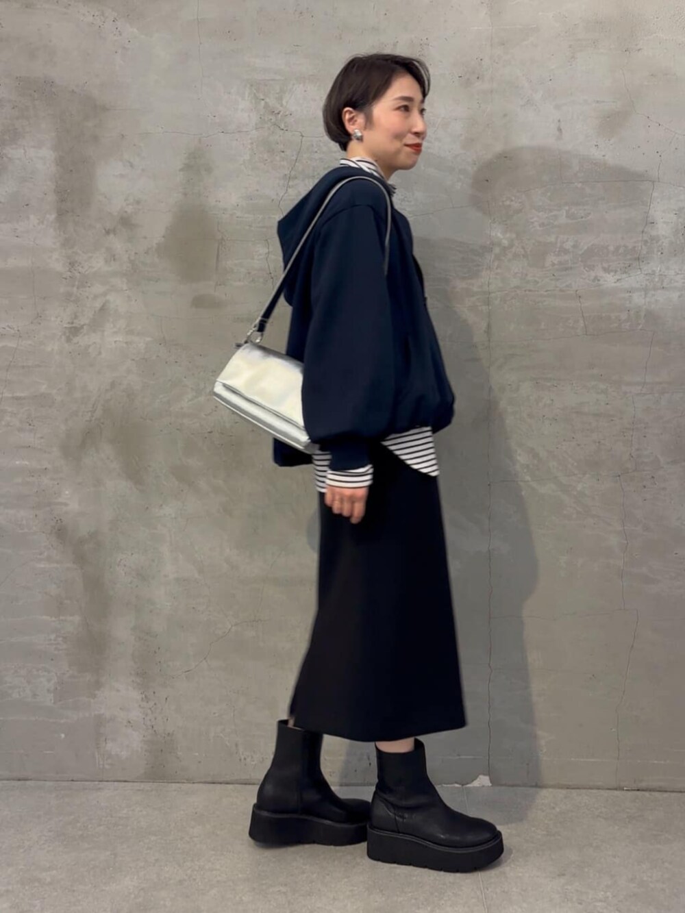 ブラック系のブーツ、ブラック系のスカート、ブルー系のパーカーを着用したレディースの冬コーディネートの3枚目の写真