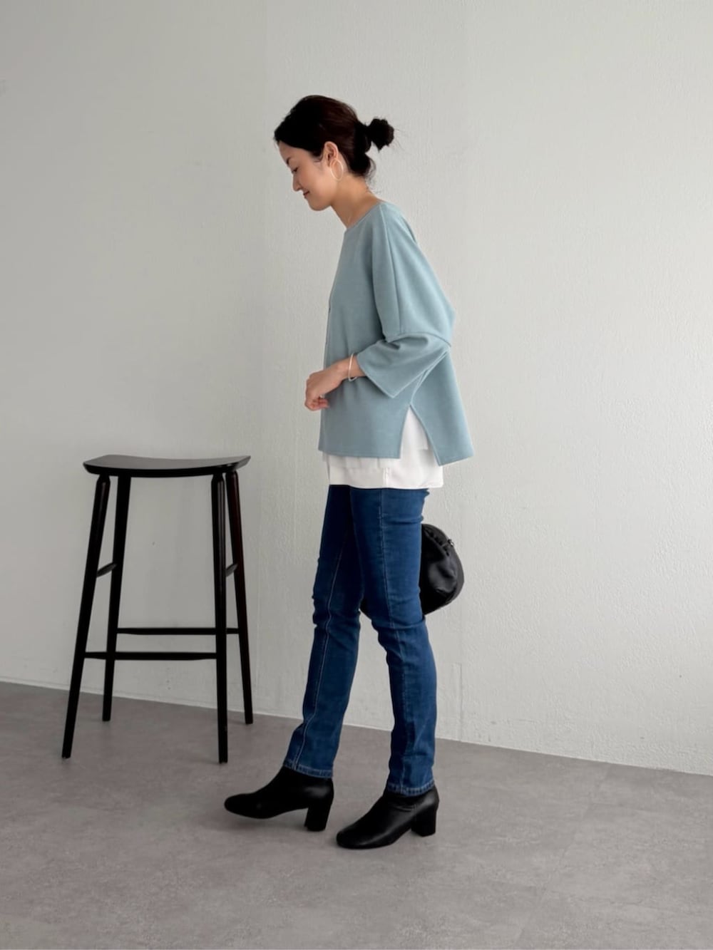 ブルー系のデニムパンツ、ブルー系のニット/セーター、ホワイト系のキャミソールを着用したレディースの夏コーディネートの2枚目の写真