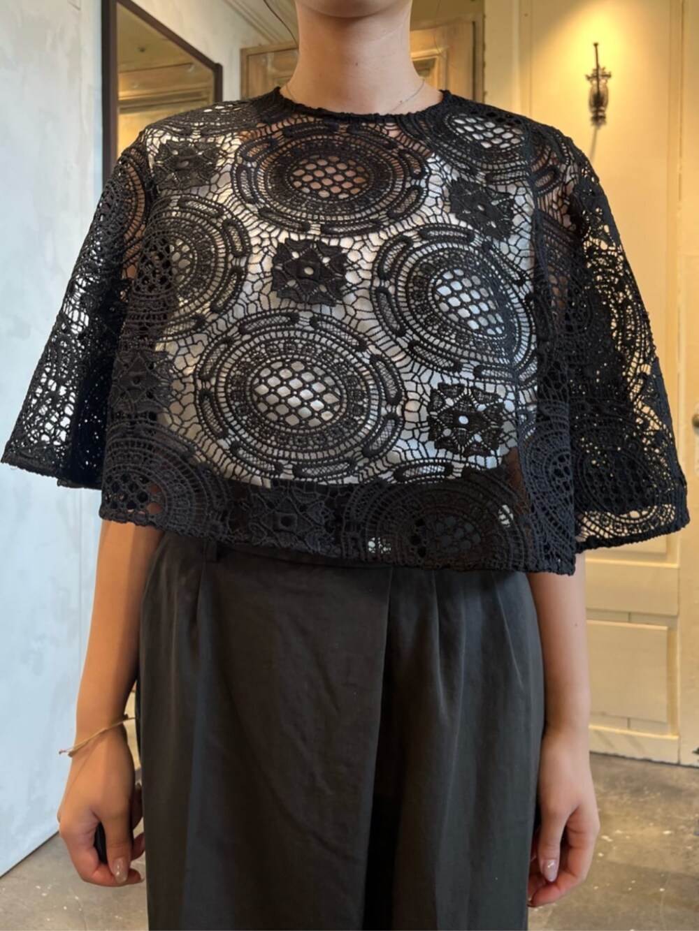 ホワイト系のタンクトップ、ブラック系のポンチョ、グレー系のその他パンツを着用したレディースの冬コーディネートの5枚目の写真