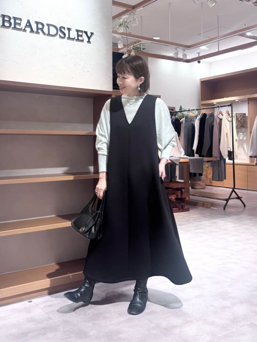 ブラック系のトートバッグ、ブラック系のジャンパースカート、ブラック系のダウンジャケット/コートを着用したレディースの冬コーディネートの4枚目の写真