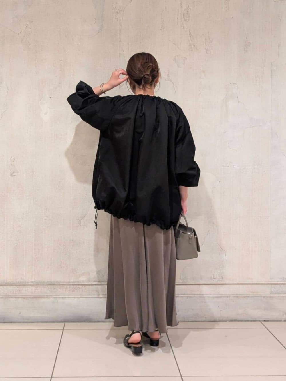 グリーン系のスカート、グレー系のハンドバッグ、ブラック系のノーカラージャケットを着用したレディースの春コーディネートの6枚目の写真