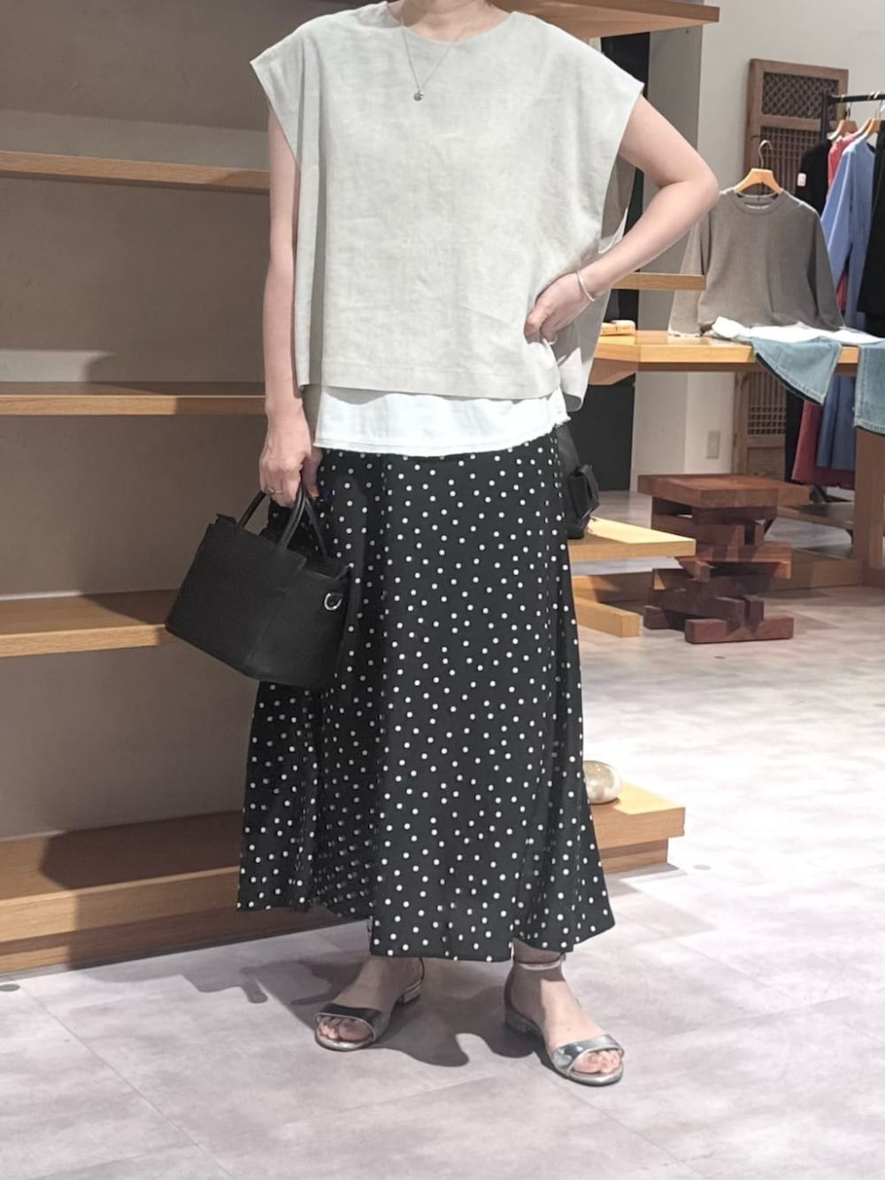 ブラック系のハンドバッグ、ブラック系のスカート、ベージュ系のシャツ/ブラウスを着用したレディースの春コーディネートの4枚目の写真