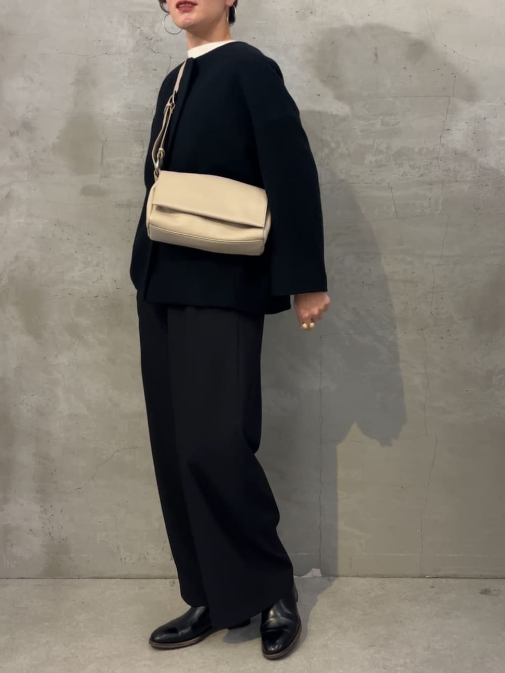 ブラック系のノーカラーコート、ブラック系のその他パンツ、ホワイト系のショルダーバッグを着用したレディースの冬コーディネートの5枚目の写真