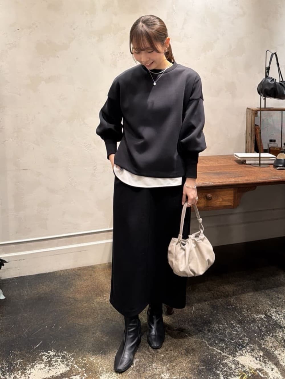 ベージュ系のショルダーバッグ、ホワイト系のシャツ/ブラウス、ブラック系のTシャツ/カットソーを着用したレディースの冬コーディネートの2枚目の写真