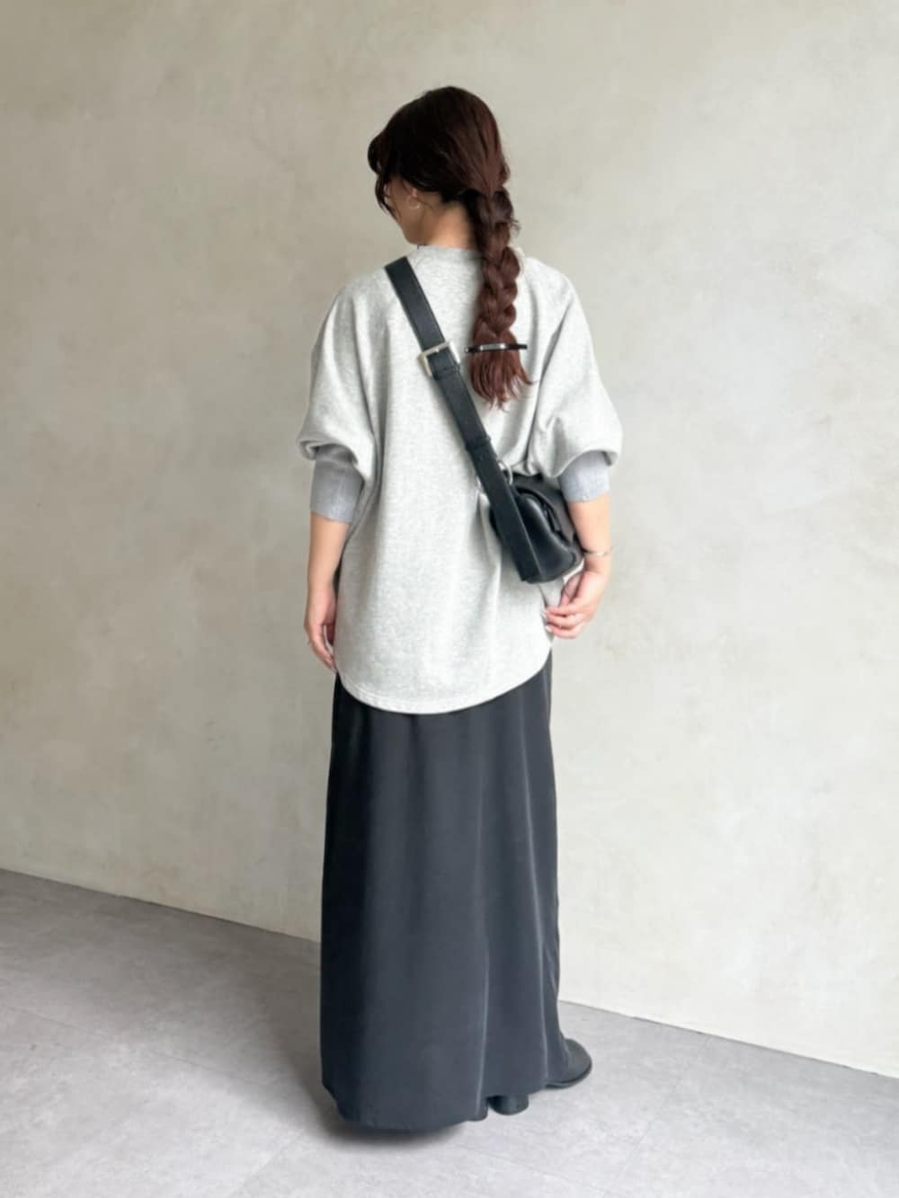 グレー系のTシャツ/カットソー、ブラック系のスカート、ブラック系のブーツを着用したレディースの秋コーディネートの4枚目の写真