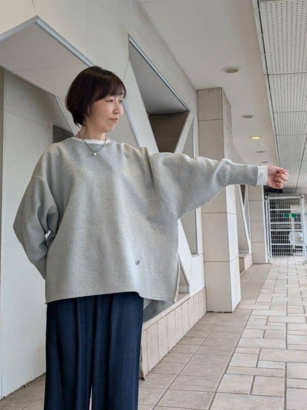 ブルー系のその他パンツ、グレー系のニット/セーター、ホワイト系のノーカラージャケットを着用したレディースの冬コーディネートの7枚目の写真